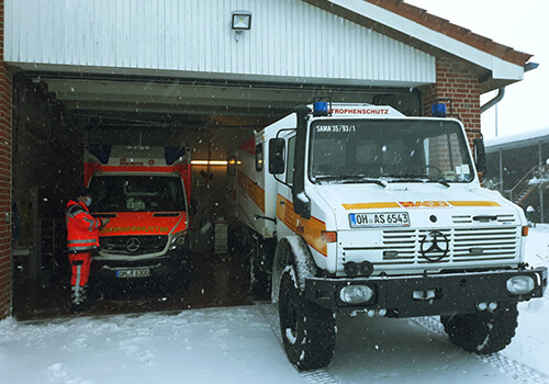 Ein Bild im Winter von einer Fahrzeughalle mit einem RTW und einem Fahrzeug vom Katastrophenschutz