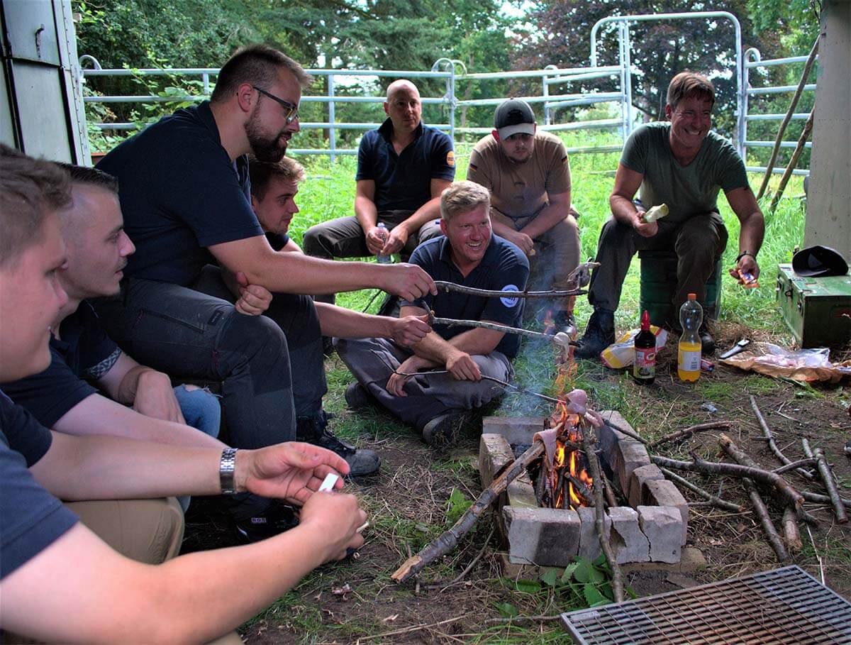 Bild von Mitarbeitenden beim Essen an einem Lagerfeuer im Teambuilding Event